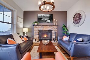 A living room with a fireplace, two sofas, a coffee table, and a wall clock.