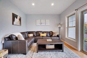 A living room with a brown leather sectional sofa, a coffee table, and a large window.