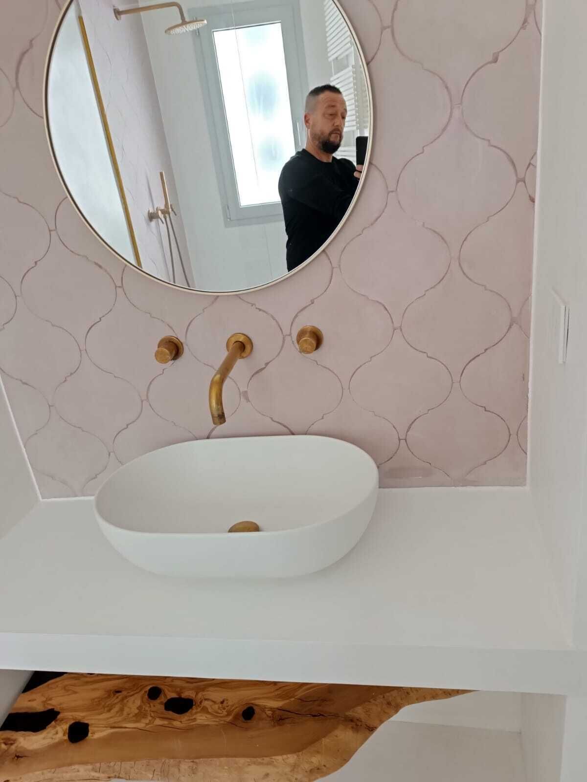 A bathroom with a round mirror, a white sink, and a patterned wall.