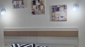 Una habitación de hotel con una cama, dos mesitas de noche y tres lámparas fijadas a la pared.