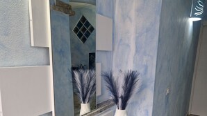 Una moderna recepción con pared de mármol, un espejo grande, un cartel de bienvenida y jarrones decorativos.