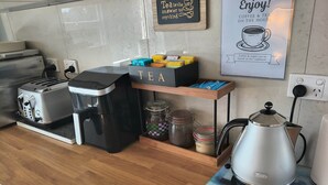 A kitchen with a coffee maker, a toaster, and a tea station.