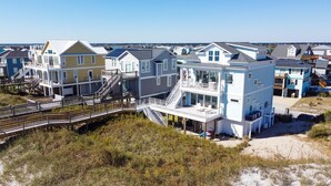 A beachfront property with multiple-story houses, a wooden boardwalk, and a sandy beach. - New Oceanfront Home | Private Beach Access (Topsail Beach)