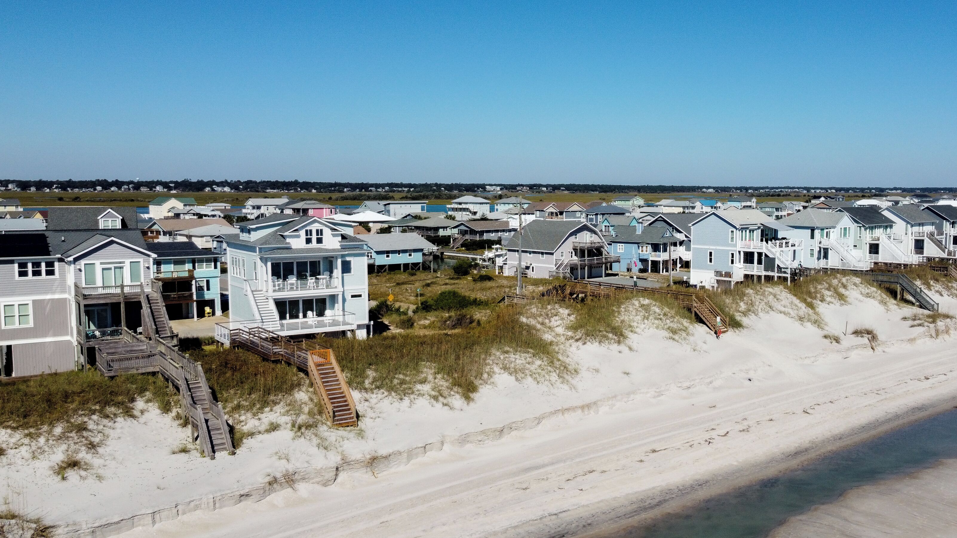 Zona residencial frente a la playa con casas que tienen balcones y acceso directo a la playa.