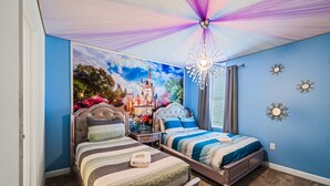 Ein Schlafzimmer mit zwei Betten, einer Kristallleuchtre und Wandmalerei zum Thema Burg.