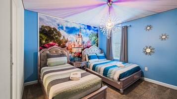 A bedroom with two beds, a chandelier, and a castle-themed wall mural.