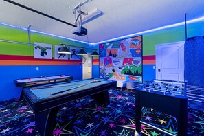 Une pièce lumineuse, équipée d’une table de billard, d’un baby-foot et d’un mur décoré d’œuvres d’art dans le style des bandes dessinées.