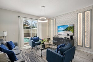 A modern living room with a pool view, a flat-screen TV, and a cozy seating area.