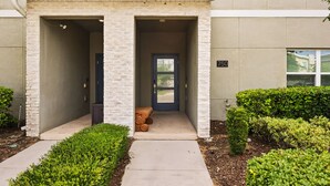 A building entrance with a covered porch, a door, and a small seating area.