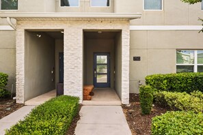 A building entrance with a covered porch, a door, and a small seating area.