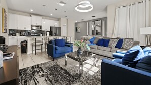 A modern living room with a sofa, coffee table, and a kitchen area in the background.