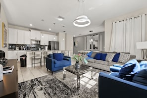 A modern living room with a sofa, coffee table, and a kitchen area in the background.