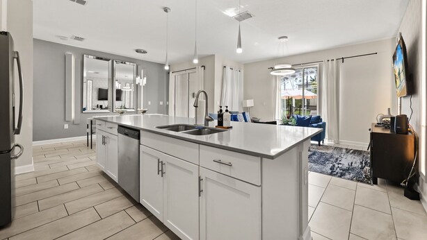 A modern kitchen with a large island, stainless steel appliances, and pendant lighting.