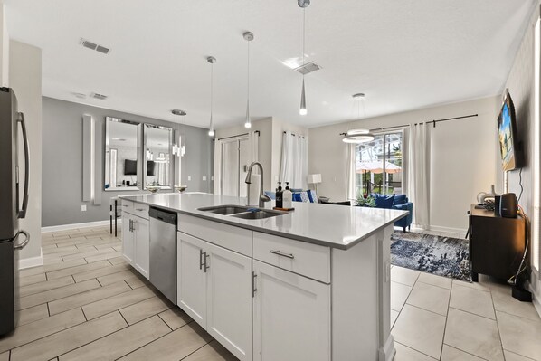 A modern kitchen with a large island, stainless steel appliances, and pendant lighting.