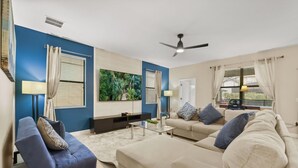 A living room with a sofa, a coffee table, a TV, and a ceiling fan.