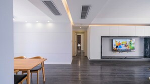 A modern living room with a dark wooden floor, white walls, and a flat-screen TV mounted on the wall. - Tyms Luxury 3BR 2BA APT Riverside (Shanghai)
