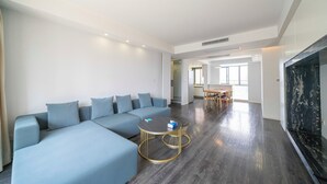 A modern living room with a sectional sofa, a round coffee table, and a dark wood floor. - Tyms Luxury 3BR 2BA APT Riverside (Shanghai)