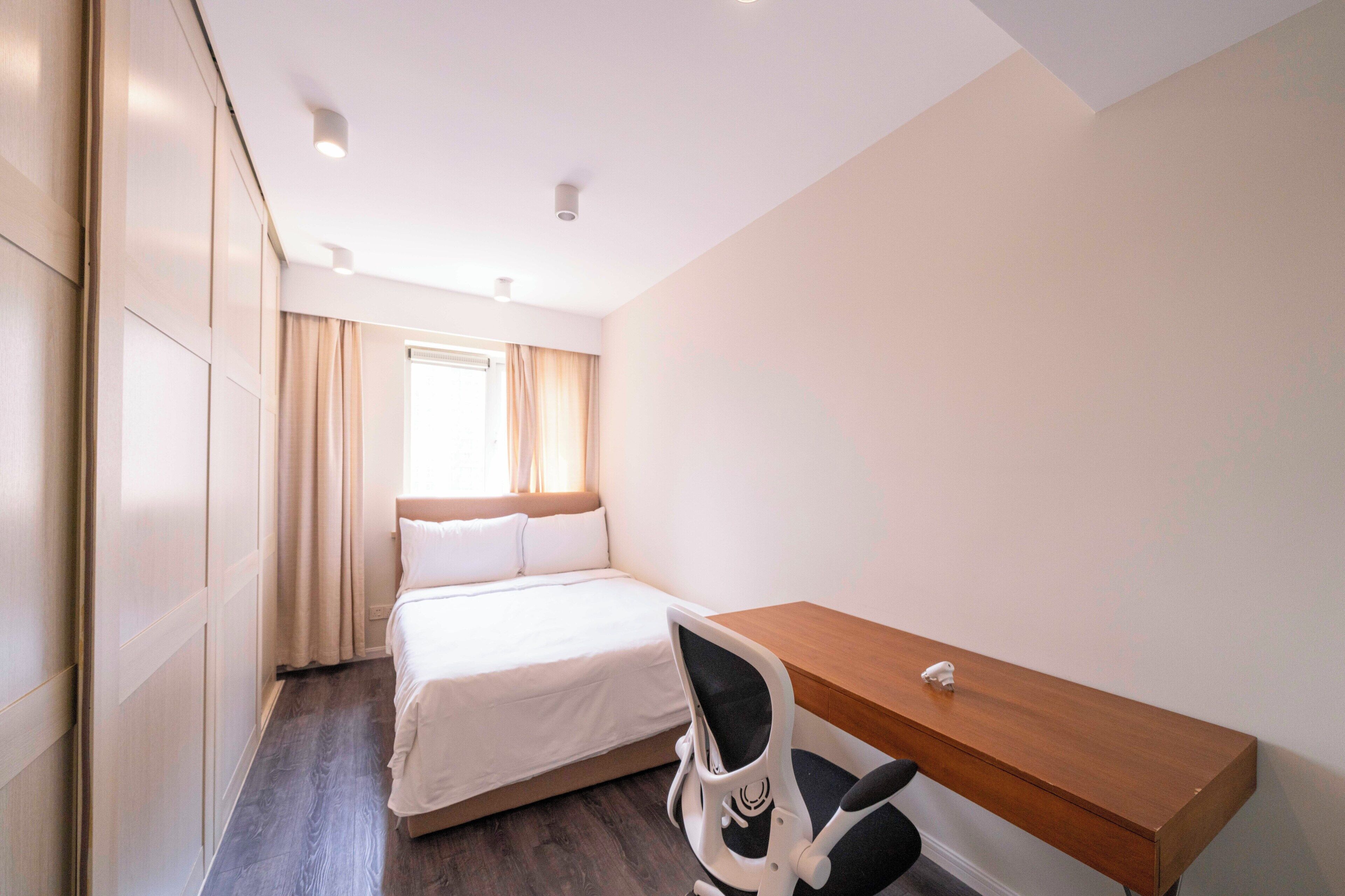 A hotel room with a bed, a desk, and a chair.