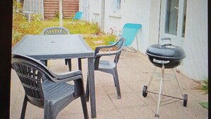 An outdoor patio with a table and chairs, a barbecue grill, and a house in the background. - Vendée farmhouse near beach and town center (L'Aiguillon-la-Presqu'île)