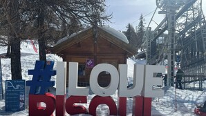 Lumipeitteinen alue, jossa on puinen mökki ja kyltti, jossa on suurilla kirjaimilla kirjoitettu teksti: ’ILQUE DICOTT’.