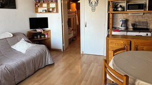 Makuuhuone, jossa on sänky, yöpöytä, televisio ja ovi, joka johtaa kylpyhuoneeseen.