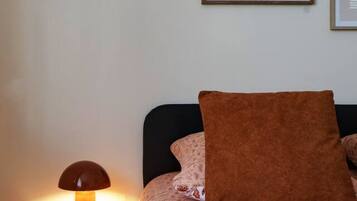 Une chambre à coucher avec un lit, une table de chevet, une lampe et une œuvre d’art abstraite accrochée au mur.