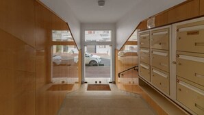 A hallway with wooden walls, a metal staircase, and a view of the street outside.
