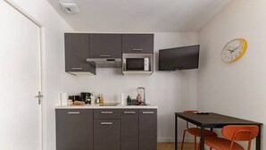 A compact kitchen with dark cabinets, a microwave, a sink, and a small dining table with two chairs.