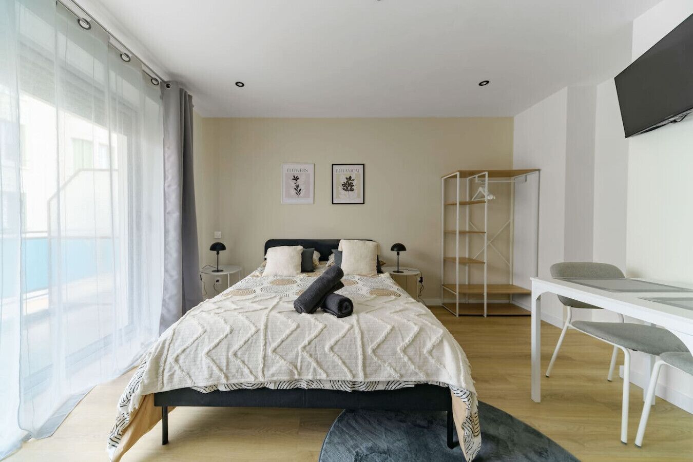 Ein modernes Schlafzimmer mit Bett, Nachttischen, einem Schreibtisch und einem Fernseher.