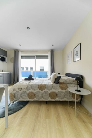 Une chambre moderne avec un lit, une table de chevet et une vue sur l’extérieur.