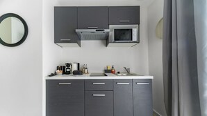 A compact kitchen with grey cabinets, a microwave, and a sink.
