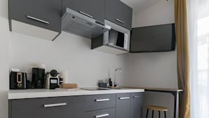 A modern kitchen with grey cabinets, a microwave, and a coffee machine.