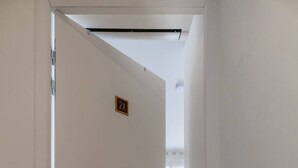 A hallway with a white door marked "2A" leading to a room with a wooden floor and a visible window.