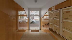 A hallway with wooden walls, a door leading outside, and a set of metal lockers on the right.