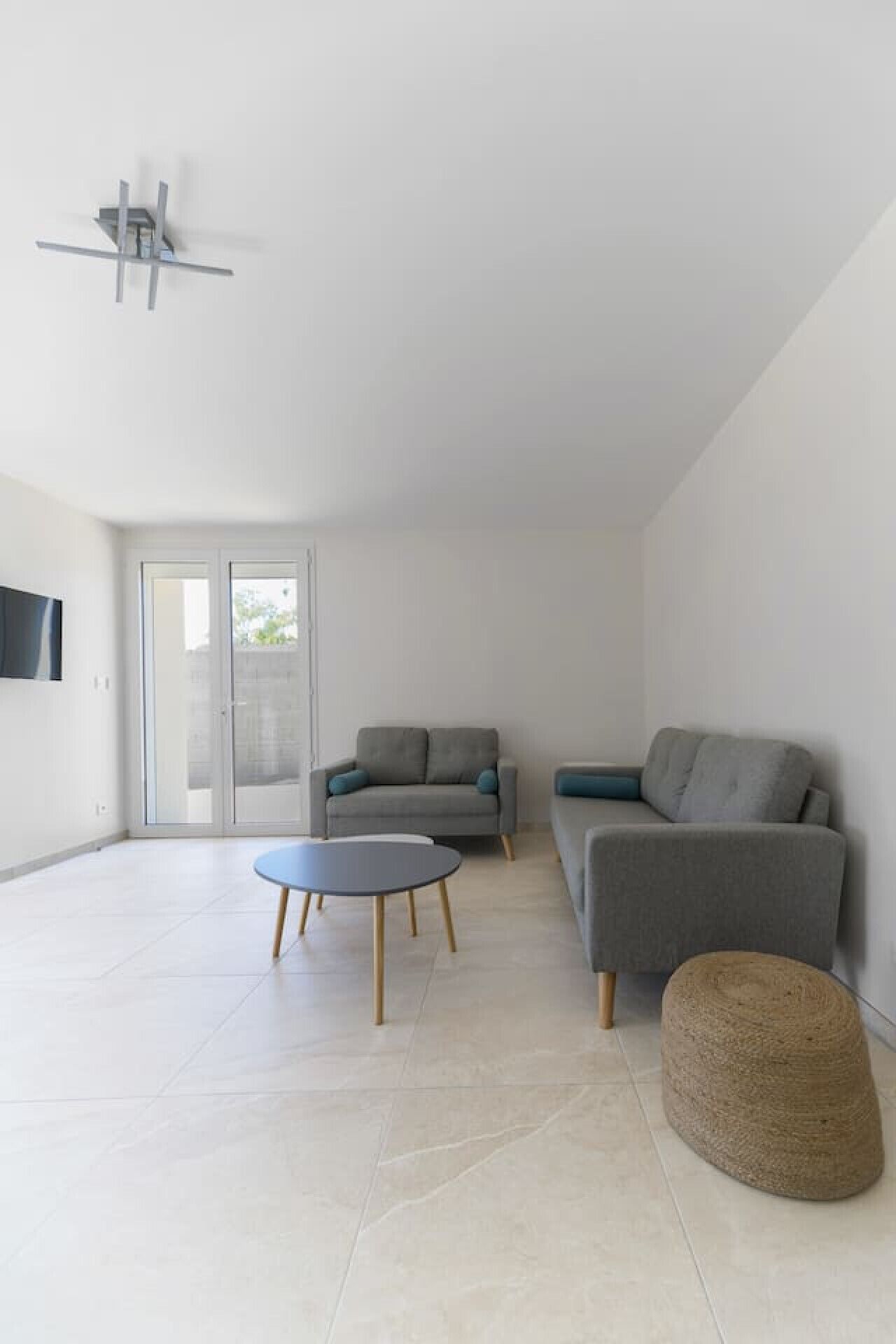 A modern living room with a grey sofa, a round coffee table, and a small ottoman.