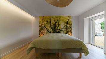 A bedroom with a bed, a large window, and a wall mural of trees.