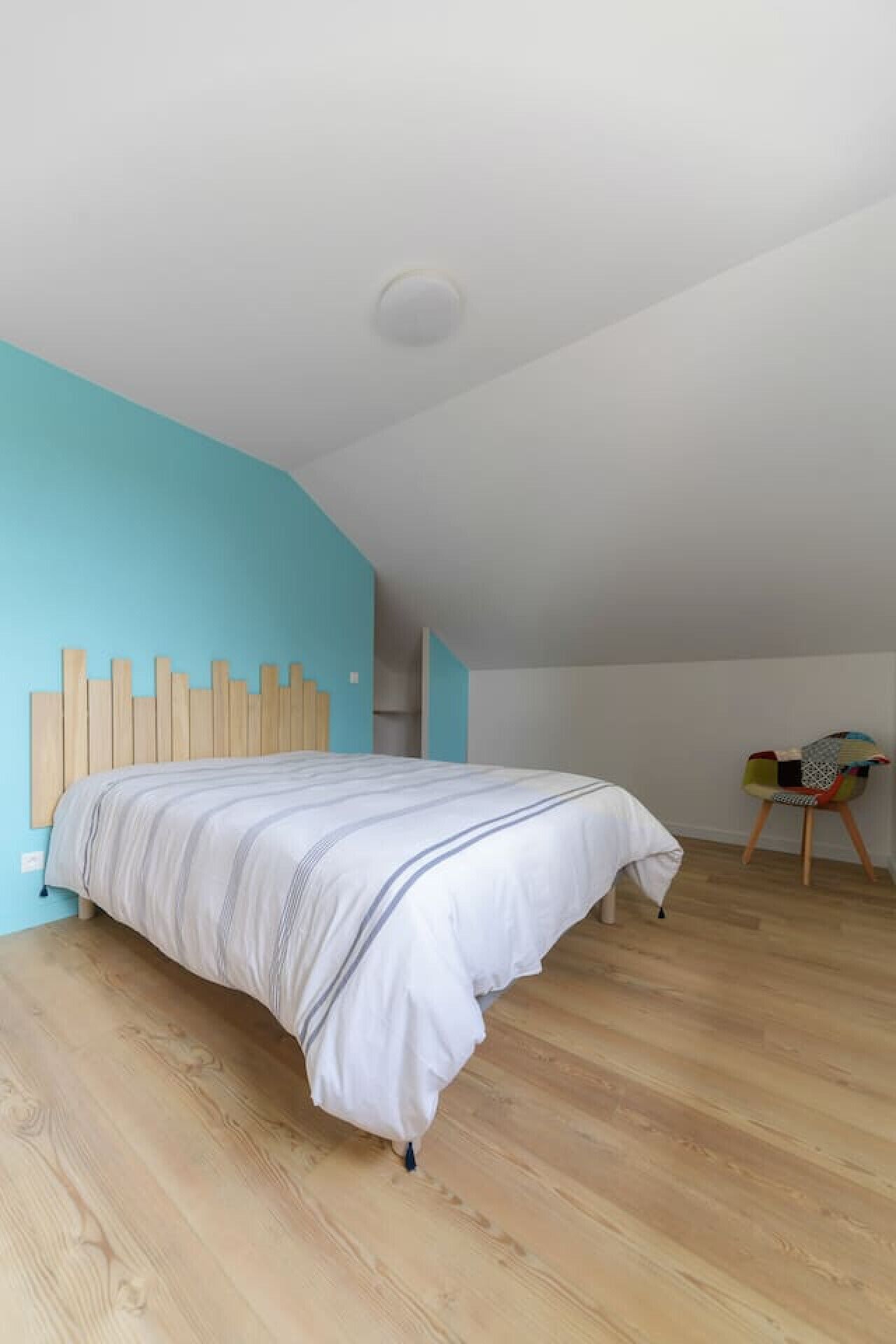 A bedroom with a wooden bed, a blue accent wall, and a wooden floor.