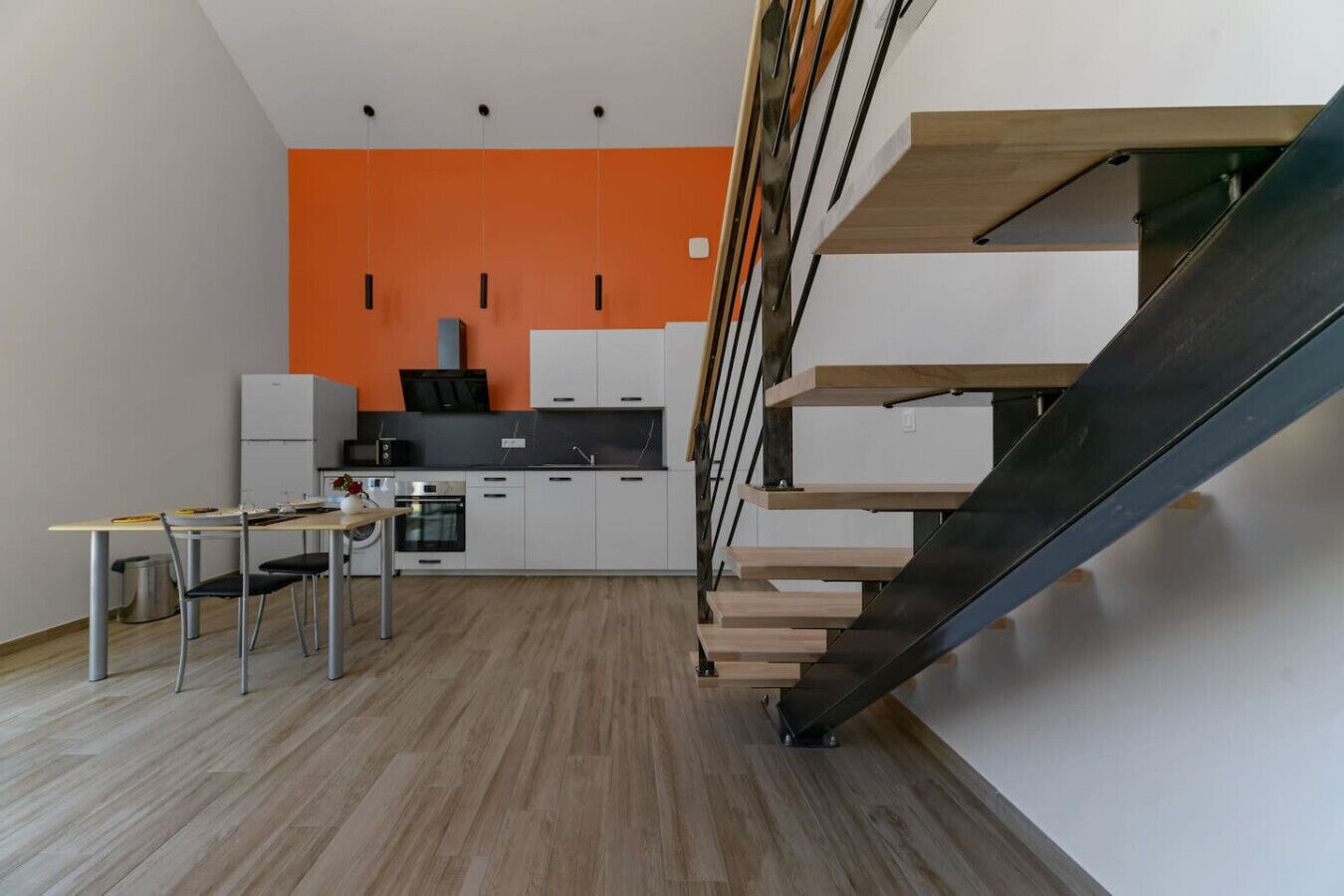 Een moderne keuken met een houten trap en een eethoek.
