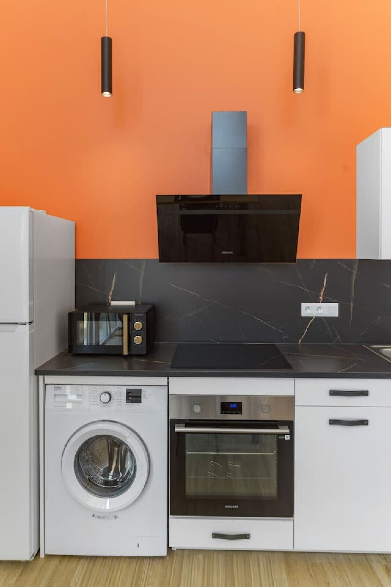 A compact kitchen with a washing machine, oven, microwave, and a toaster.