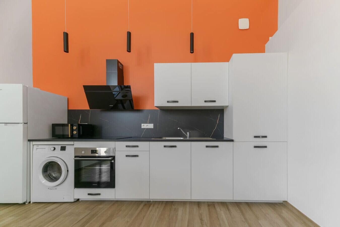Una cucina funzionale con lavatrice, forno, microonde e lavandino.