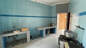 Een keuken met blauwe tegels, een gasfornuis, een spoelbak en een aanrecht met diverse spullen.