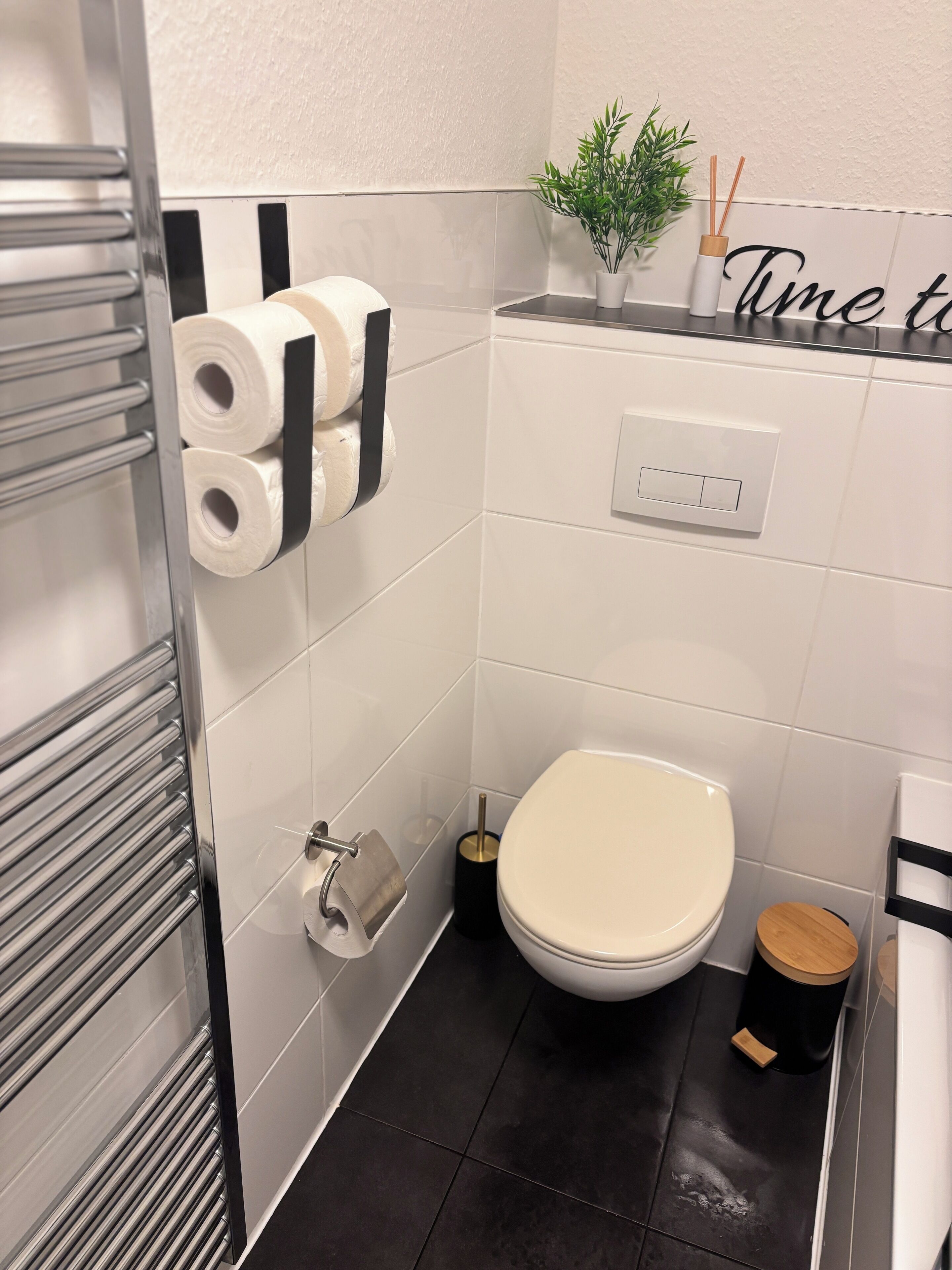 Une salle de bain moderne équipée de toilettes, d’un porte-serviettes et d’un support à papier toilette.