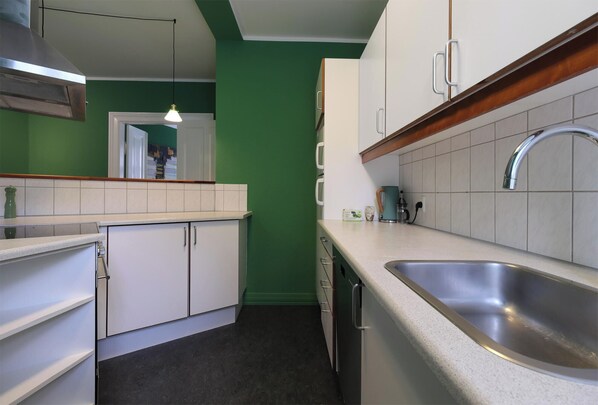 A kitchen with white cabinets, a stainless steel sink, and a green wall.