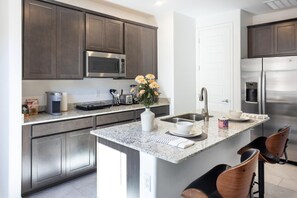 A modern kitchen with dark cabinets, stainless steel appliances, a granite countertop, and a central island with seating. - Enchanting apartment in Tucson (Tucson)