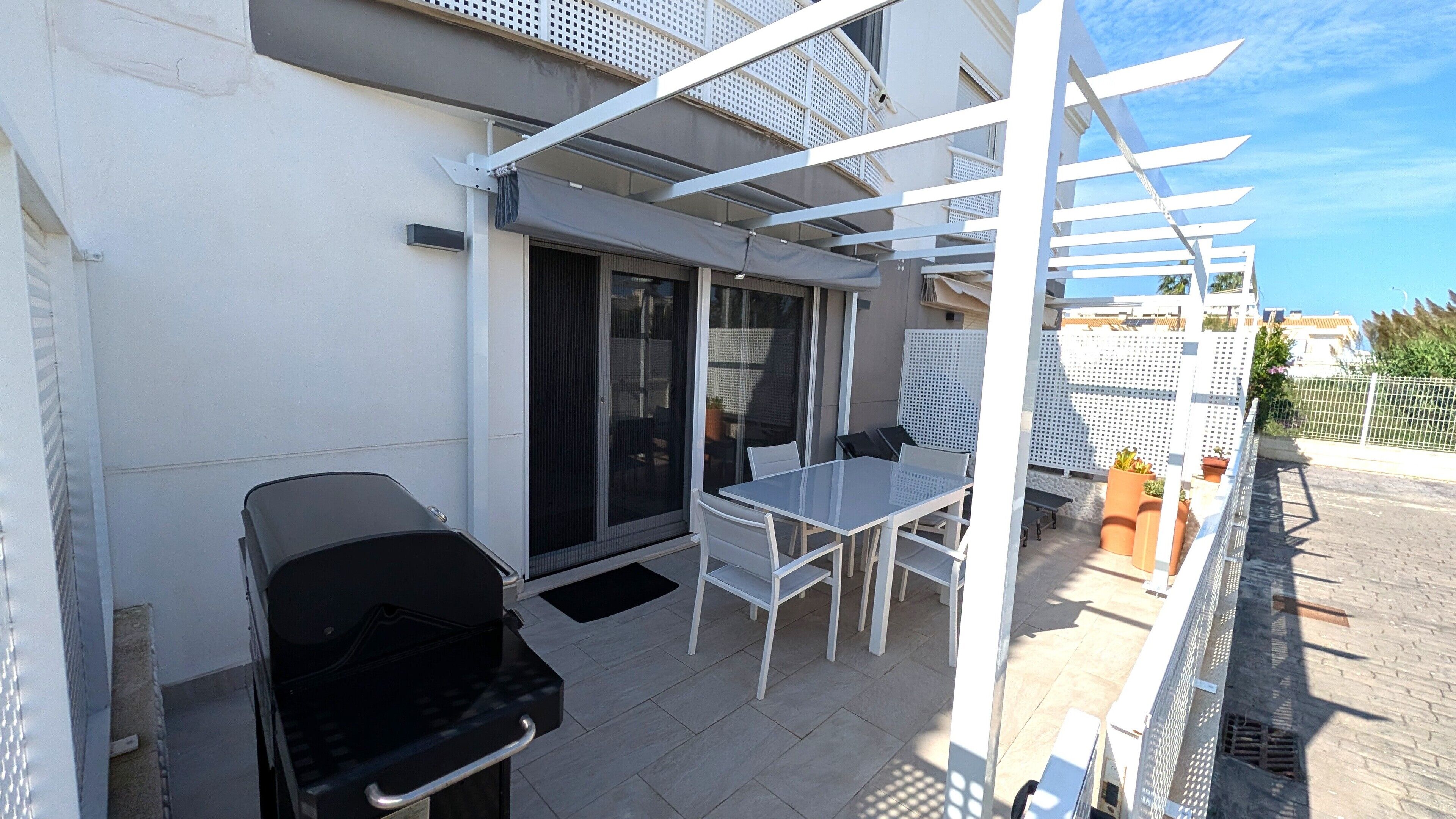 A balcony with a grill, a table, and chairs.