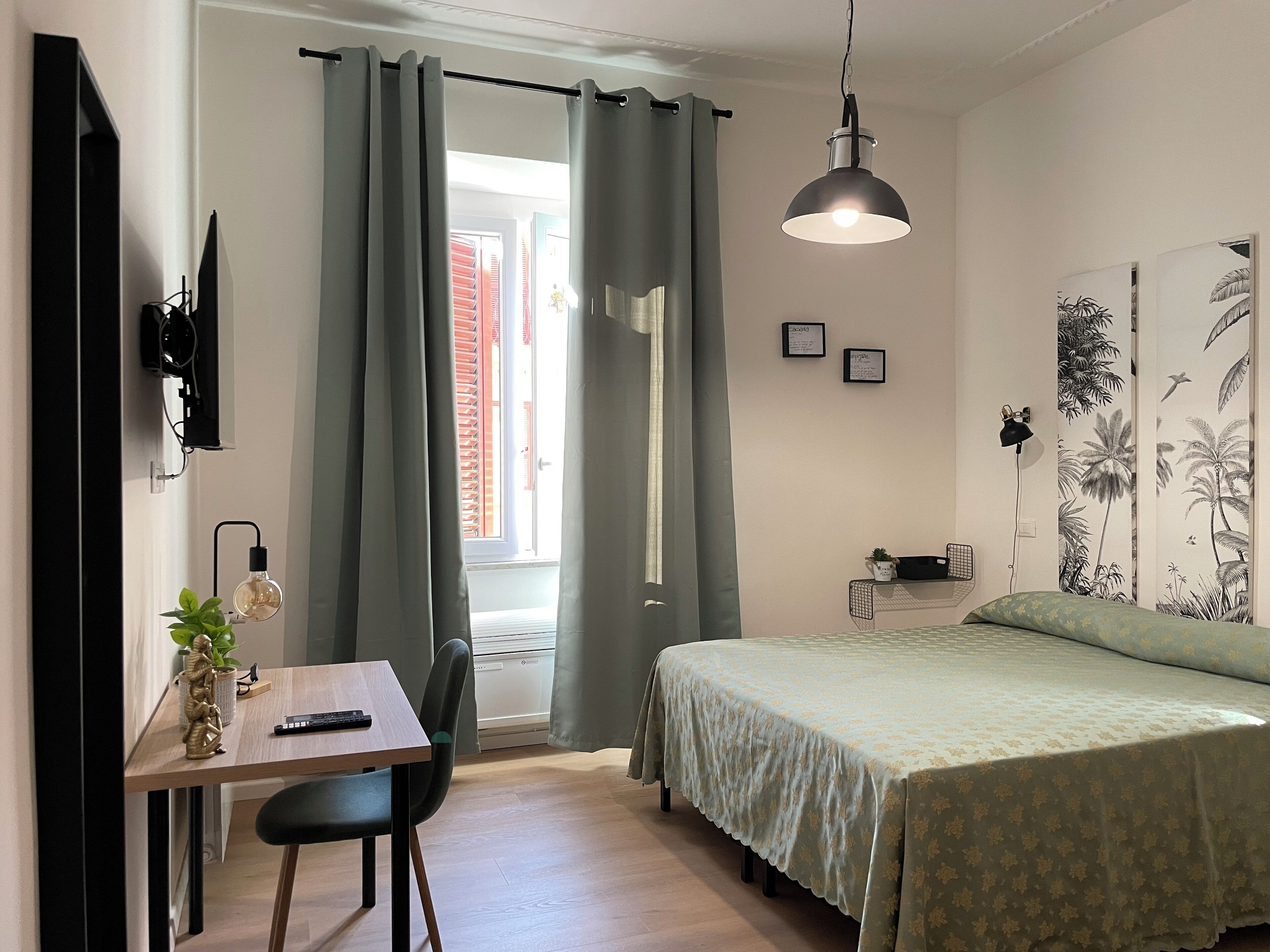 Un dormitorio con cama, escritorio con silla, lámpara colgante y ventana con cortinas.