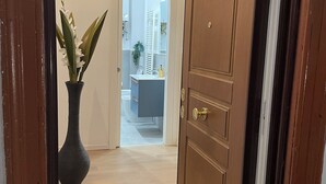 A hallway leading to a bathroom with a wooden door, a potted plant, and a visible toilet. - Enjoy Rhome, your apartment just steps from the Basilica of Santa M. Maggiore (Roma)