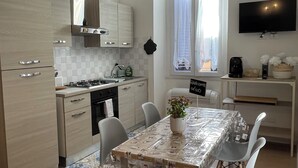 A modern kitchen with a dining area, featuring a table with chairs, a TV mounted on the wall, and a window with curtains. - Enjoy Rhome, your apartment just steps from the Basilica of Santa M. Maggiore (Roma)