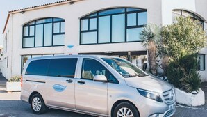 Una camioneta plateada estacionada frente a un edificio con grandes ventanales y fachada blanca.