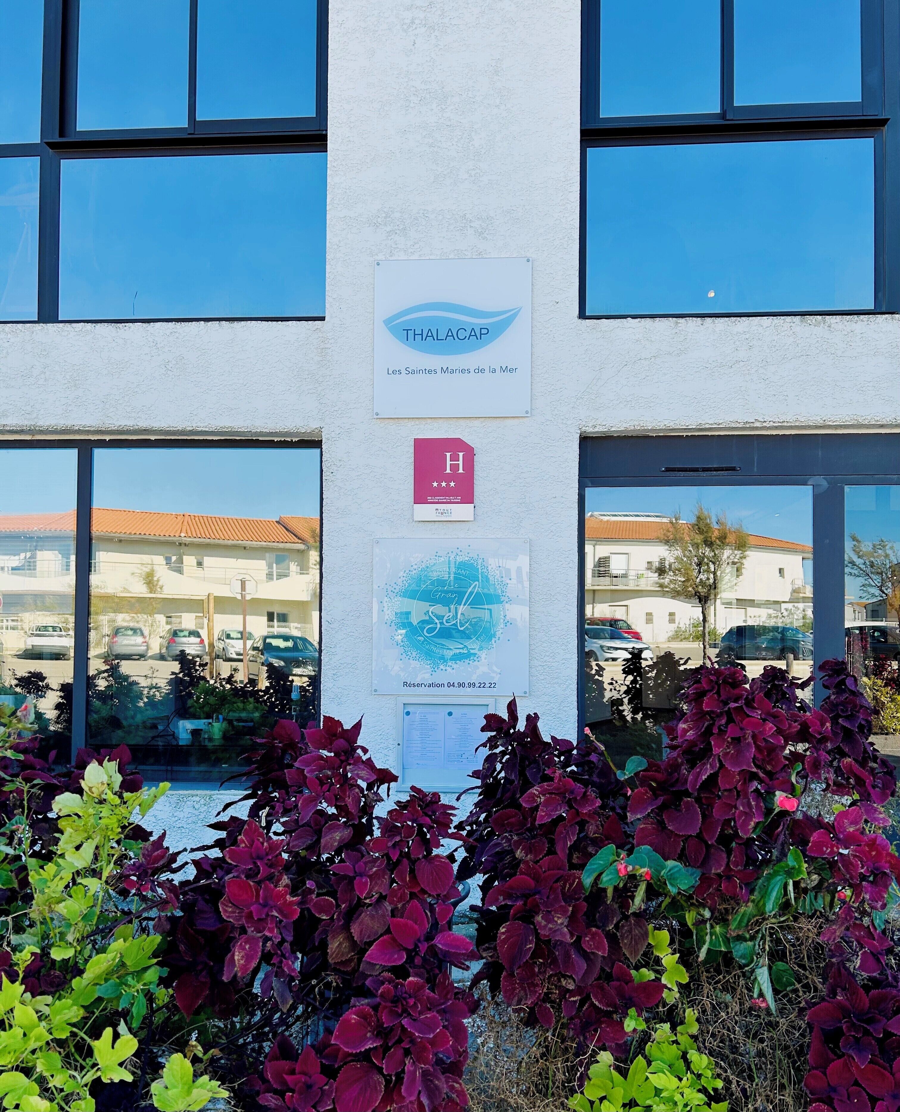 A building with a sign for 'THALACAP' and a parking reservation notice.